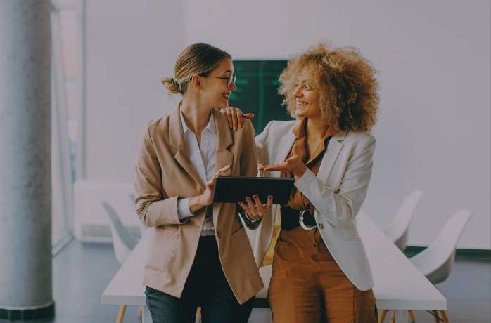 two young woman talking next to each other at office