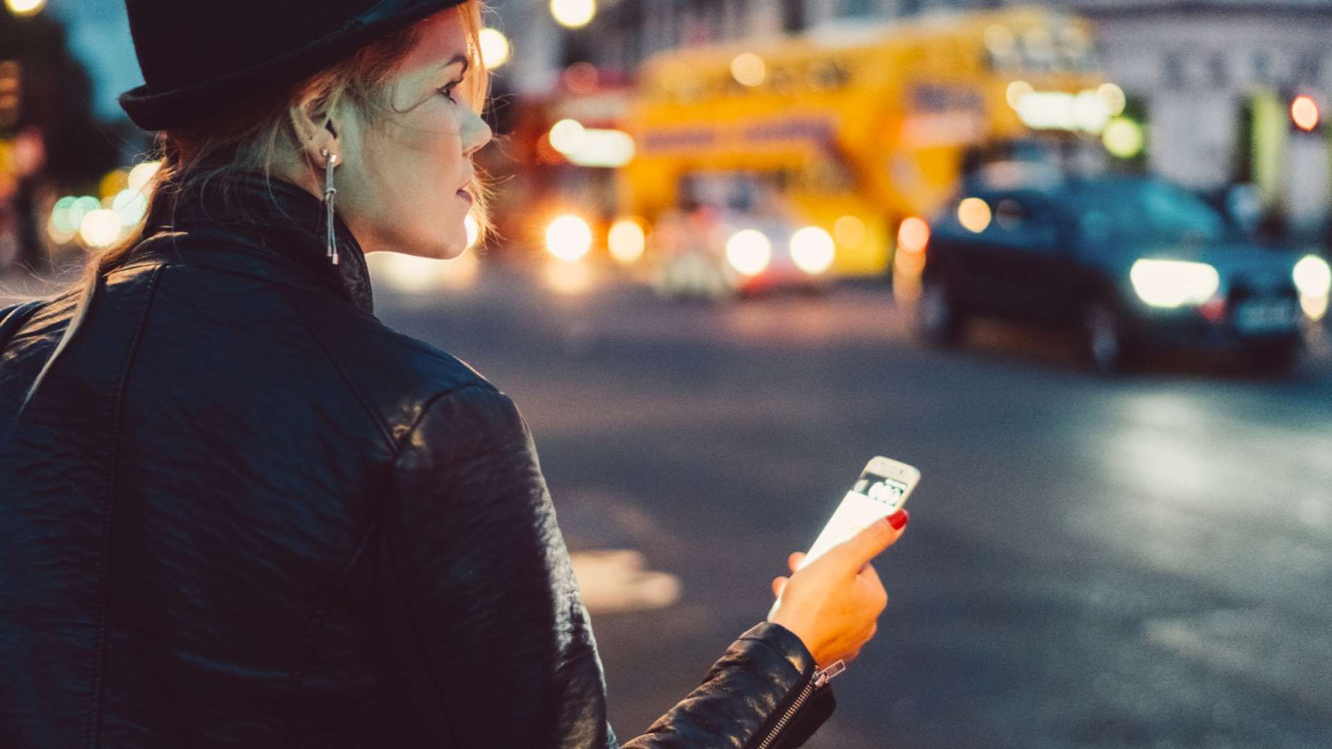 woman holding phone in the middle of the city