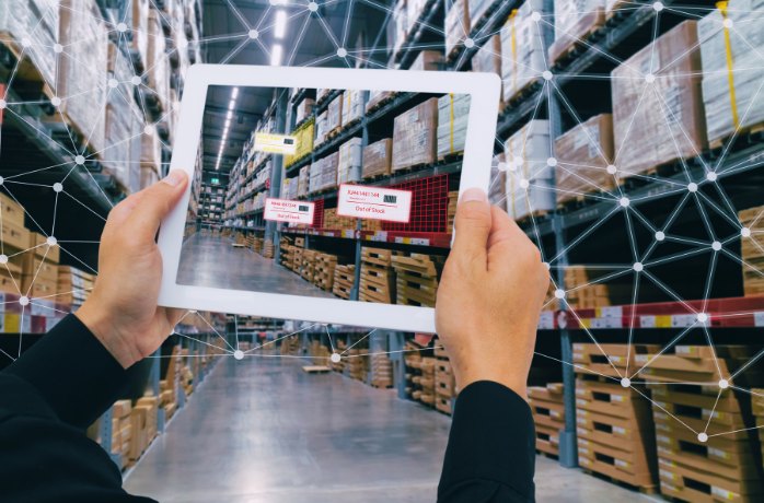 hands holding tablet in a warehouse aisle for smart inventory